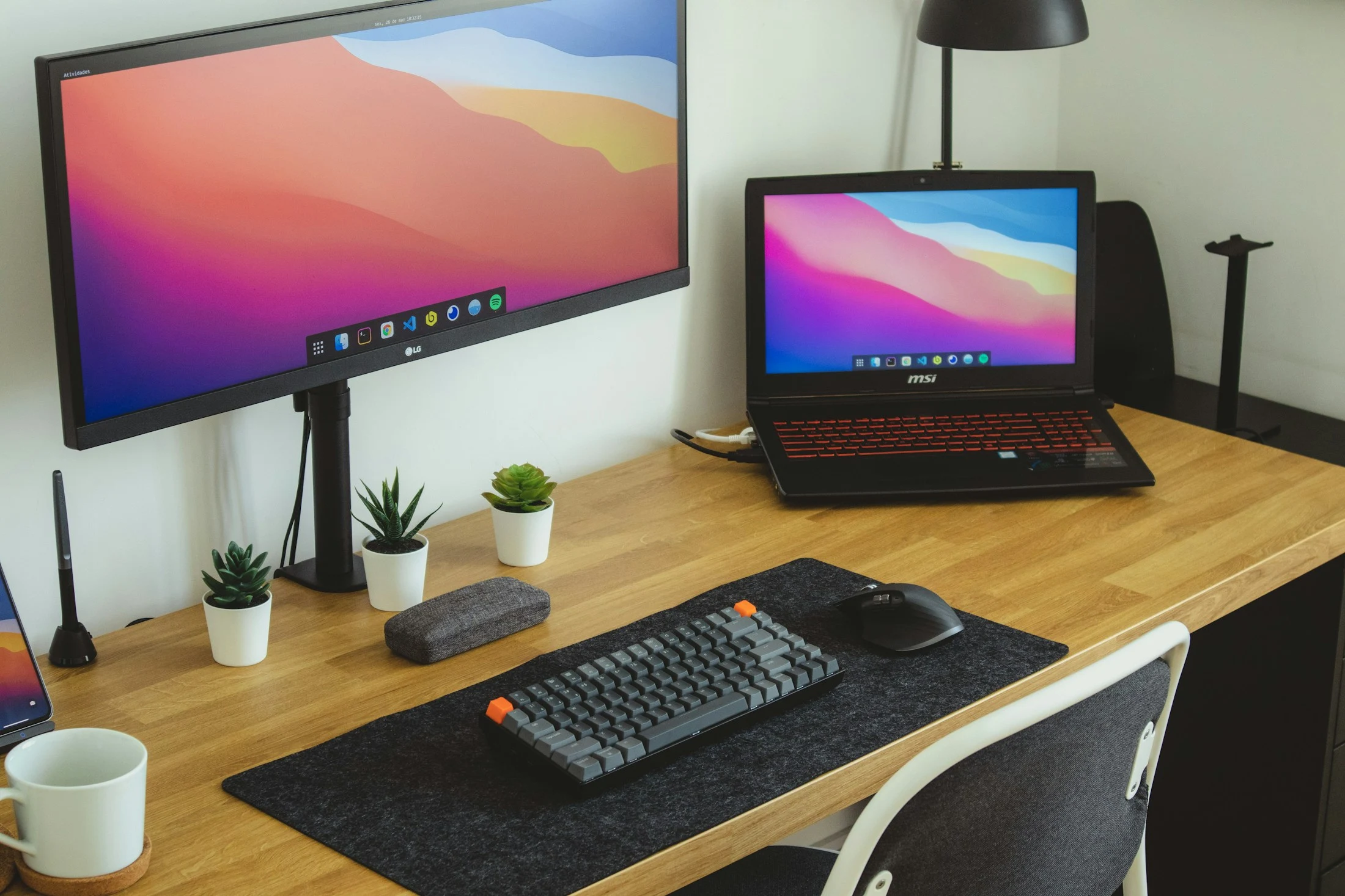 A monitor, laptop and keyboard arranged on a timber desk