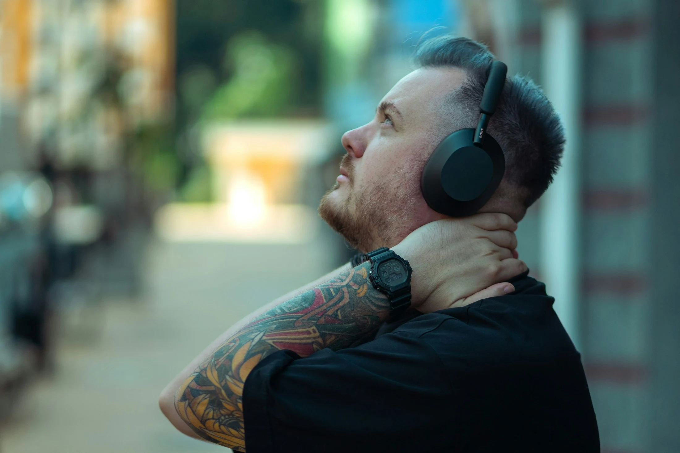 A person listening to over-ear headphones outdoors